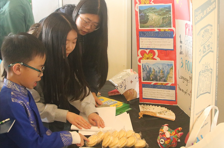 Sophia and Joyce helping a child create paper fans