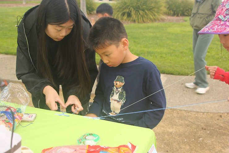 Joyce Zhang instructing a boy how to make a friendship bracelet